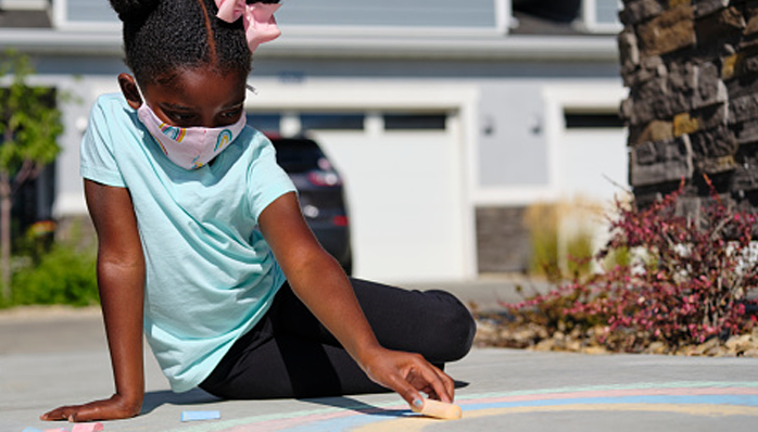 Image of a girl playing with chalk on pavement.