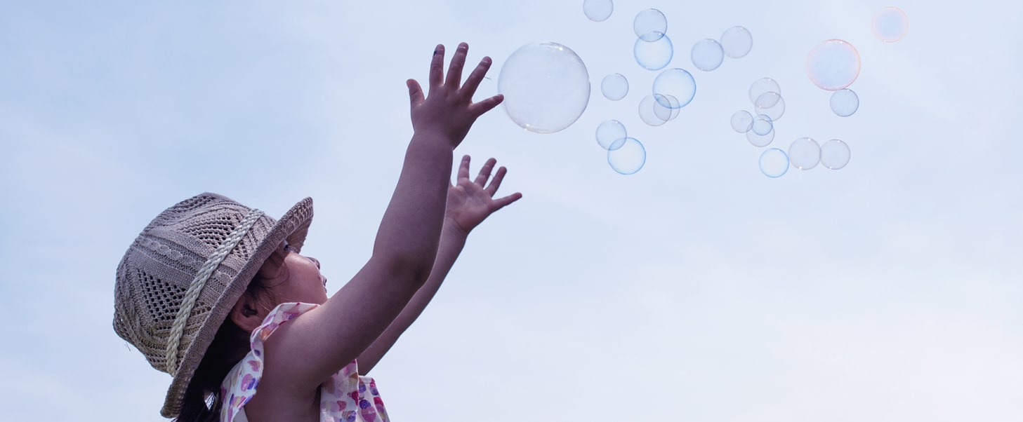 Image of a girl catching bubbles in the air.